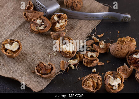 Walnüsse und einen Nussknacker auf eine Tabelle mit Sackleinen abgedeckt Stockfoto