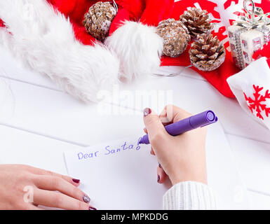 Weibliche schreiben Wunschliste in Notebook in der Nähe von Weihnachten Geschenke Stockfoto