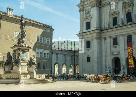 Der barocke Salzburger Dom vom Domplatz aus gesehen. Pferde und Kutschen warten darauf, Touristen für eine Stadtrundfahrt zu nehmen. Stockfoto