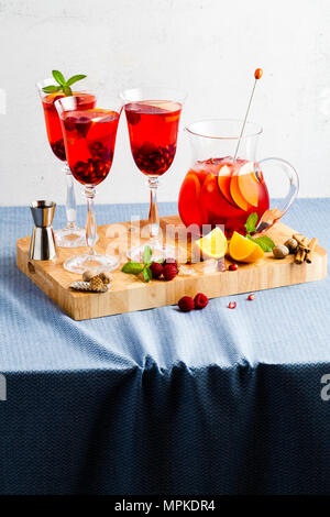Frische Sommer rote Sangria aus reifen Früchten und Beeren sowie Wein auf dem Tisch in Gläsern und einer Karaffe. Gewürzen und Minze Stockfoto