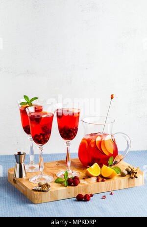 Frische Sommer rote Sangria aus reifen Früchten und Beeren sowie Wein auf dem Tisch in Gläsern und einer Karaffe. Gewürzen und Minze Stockfoto