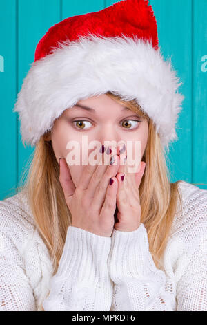 Der Weihnachtszeit. Junge Frau mit Santa Claus hat roten Kleid auf blauem Hintergrund. Überraschten Gesichtsausdruck. Stockfoto