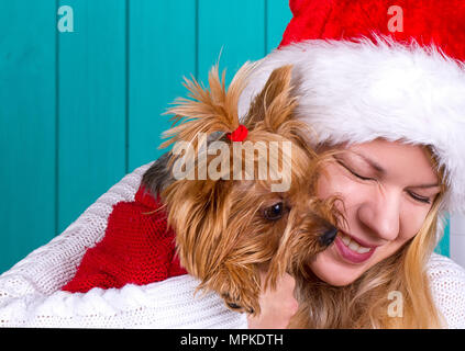 Schöne Mädchen in santa Kappe mit yorkie Hund im roten Pullover Stockfoto