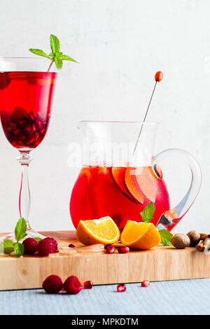 Frische Sommer rote Sangria aus reifen Früchten und Beeren sowie Wein auf dem Tisch in Gläsern und einer Karaffe. Gewürzen und Minze Stockfoto