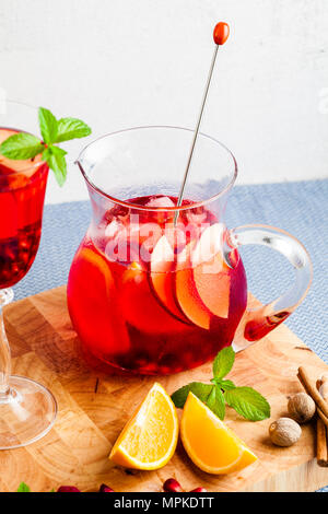 Frische Sommer rote Sangria aus reifen Früchten und Beeren sowie Wein auf dem Tisch in Gläsern und einer Karaffe. Gewürzen und Minze Stockfoto