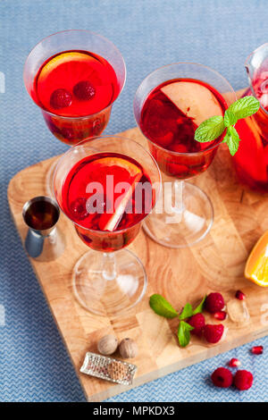 Frische Sommer rote Sangria aus reifen Früchten und Beeren sowie Wein auf dem Tisch in Gläsern und einer Karaffe. Gewürzen und Minze Stockfoto