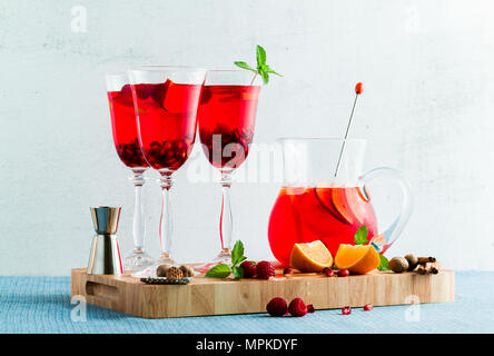 Frische Sommer rote Sangria aus reifen Früchten und Beeren sowie Wein auf dem Tisch in Gläsern und einer Karaffe. Gewürzen und Minze Stockfoto