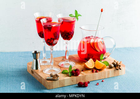 Frische Sommer rote Sangria aus reifen Früchten und Beeren sowie Wein auf dem Tisch in Gläsern und einer Karaffe. Gewürzen und Minze Stockfoto