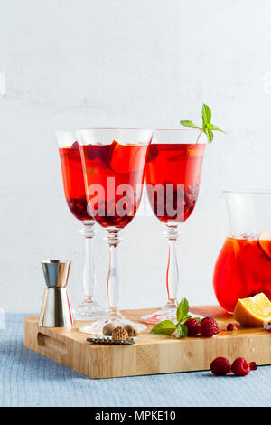 Frische Sommer rote Sangria aus reifen Früchten und Beeren sowie Wein auf dem Tisch in Gläsern und einer Karaffe. Gewürzen und Minze Stockfoto
