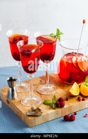 Frische Sommer rote Sangria aus reifen Früchten und Beeren sowie Wein auf dem Tisch in Gläsern und einer Karaffe. Gewürzen und Minze Stockfoto