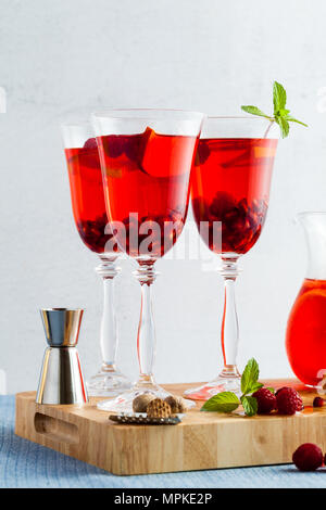 Frische Sommer rote Sangria aus reifen Früchten und Beeren sowie Wein auf dem Tisch in Gläsern und einer Karaffe. Gewürzen und Minze Stockfoto
