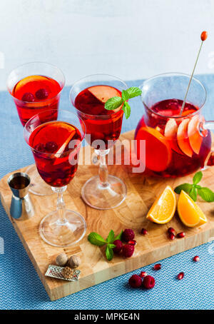 Frische Sommer rote Sangria aus reifen Früchten und Beeren sowie Wein auf dem Tisch in Gläsern und einer Karaffe. Gewürzen und Minze Stockfoto
