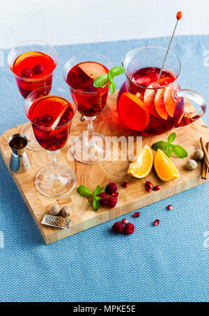 Frische Sommer rote Sangria aus reifen Früchten und Beeren sowie Wein auf dem Tisch in Gläsern und einer Karaffe. Gewürzen und Minze Stockfoto