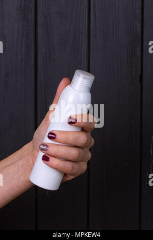 Woman's schöne Hände mit care Creme Tube auf dem schwarzen Hintergrund Stockfoto