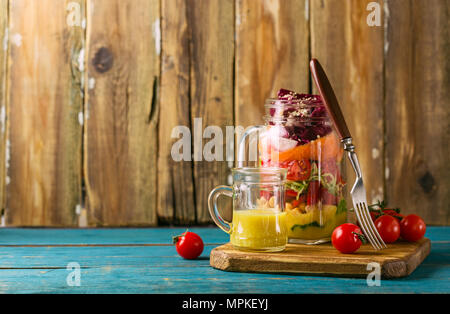 Gesunde hausgemachte Mason Jar-Salat mit Kichererbsen, Mais, Karotten, Gurken, Paprika, Radieschen, Rucola und Spinat - gesunde Ernährung, Diät oder Detox, Veg Stockfoto