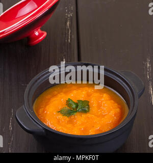 Kürbis Suppe in einer kleinen schwarzen Topf. gegen einen dunklen Hintergrund Stockfoto