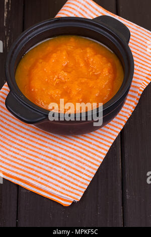 Kürbis Suppe in einer kleinen schwarzen Topf. gegen einen dunklen Hintergrund Stockfoto