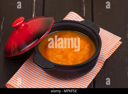 Kürbis Suppe in einer kleinen schwarzen Topf. gegen einen dunklen Hintergrund Stockfoto