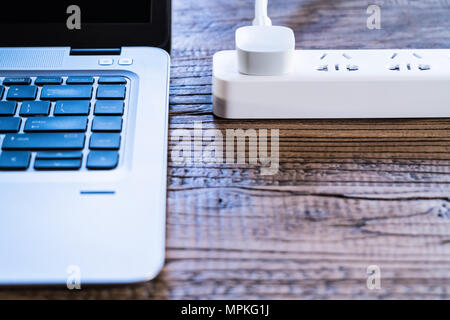 Computer Laptop und weißen Stecker Buchse auf hölzernen Tisch flach Zusammensetzung Draufsicht mit Kopie Raum Stockfoto