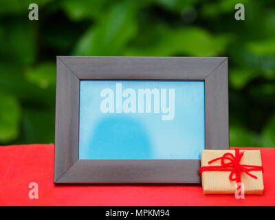Bilderrahmen mit Geschenk auf rotem Hintergrund Stockfoto