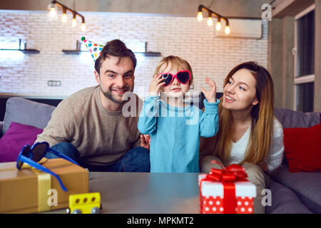 Eltern mit Geburtstag Kuchen ihr Kind gratulieren. Stockfoto