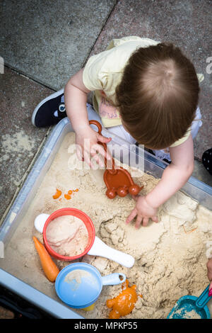 18 Monate altes Mädchen Kleinkind spielen in einer Sandkuhle Stockfoto