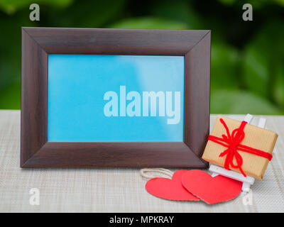 Bilderrahmen mit Geschenk auf rotem Hintergrund Stockfoto