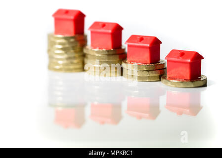 Miniatur Häuser ruhen auf Neue pound Münze Stapel Konzept für property Ladder, Hypothek und Real Estate Investment Stockfoto