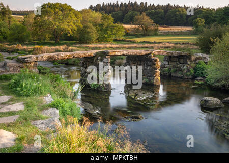 An einem warmen Sommerabend, nach den Touristen abreisen, die East Dart River rieselt unter dem wunderschönen Granit Postbridge Clapper Bridge an in Stockfoto