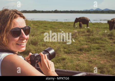 Frau auf asiatischen Wildlife Safari. Dame ein Foto der Herde Elefanten mit Ihrer Kamera. Stockfoto