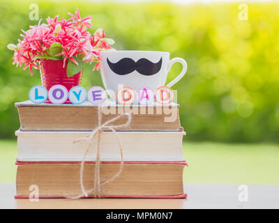 Vatertag Konzept. Liebe papa Alphabets auf Stapel Bücher, Geschenke, Tee Tasse mit schwarzen Schnurrbart und Blume auf Hintergrund Stockfoto