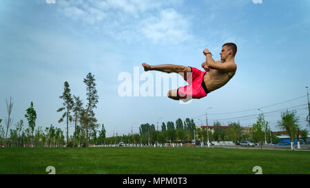 Austrickst, auf Rasen im Park. Man macht Kick in Springe mit drehen. Martial Arts. Stockfoto