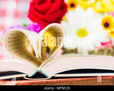 Geöffnete Buch und Seiten die Herzform mit Blume im backgroung. Liebe und Valentinstag Konzept. Stockfoto