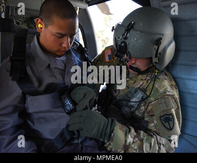 Us-Armee Sgt. Dustin Keenan, Abteilung 1, Charlie Co., 2-238 Allgemeine Unterstützung Aviation Battalion, South Carolina Army National Guard, hilft bei der simulierten Umsiedler auf ein UH-60 Blackhawk während eines Hurrikans evakuierungsübung als Teil des wachsamen Schutz 17 in der Gegend von Savannah, Georgia, 29. März. Wachsam Guard 17 ist eine gemeinsame regionale Training Übung für die South Carolina National Guard eine Gelegenheit, die Zusammenarbeit und die Beziehungen mit lokalen, staatlichen regionalen zivilen, militärischen und föderalen Partnern in Vorbereitung auf Notfälle und Katastrophen zu verbessern. (U.S. Army National Guar Stockfoto