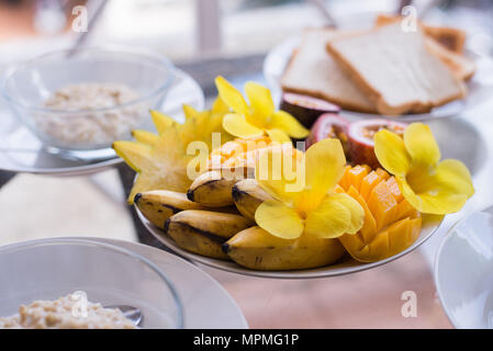 Mango, Banane, Passion Fruit Bowl garniert mit frischem Obst und Blumen Stockfoto