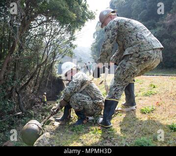 170330-N-SD 711-0143 SASEBO, Japan (30. März 2017) Chief Utilitiesman Georgios Georgiadis und Builder 2. Klasse Jorge Aviles, sowohl zu Naval Mobile Konstruktion Bataillon (NMCB) 5, ein Grabstein aus einem Entwässerungsgraben an Hario Shima Ordnance Facility hoist zugeordnet. (U.S. Marine Foto von Mass Communication Specialist Seaman Geoffrey S. Barham/Freigegeben) Stockfoto