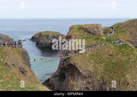 Carrick-a-Rede Rope Bridge Carrick-a-Rede Rope Bridge in Nordirland, die Menschen über die Brücke, auf der Atlantischen Ozean, schöne Steine Stockfoto