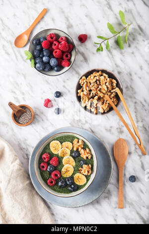 Buddha Schüssel grünem Chia Pudding mit Bananenscheiben, Blaubeeren, Himbeeren und Walnüsse Stockfoto