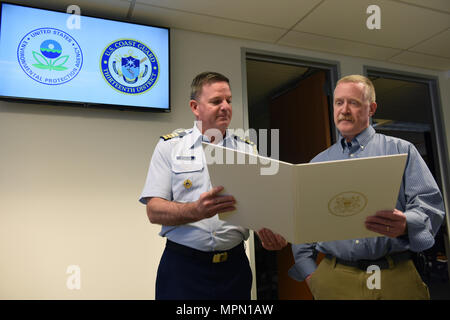 Kapitän Brendan McPherson, Stabschef, Coast Guard 13. Bezirk, präsentiert die verdienstvollen Public Service Award an Chris Field, Emergency Response Program Manager für die U.S. Environmental Protection Agency, April 6, 2017. Feld zieht sich am 26.04.29, 2017, mit 31 Jahren der föderale Dienst, 28 von denen, die er an der EPA serviert. U.S. Coast Guard Foto von Petty Officer 2. Klasse Ali Flockerzi. Stockfoto