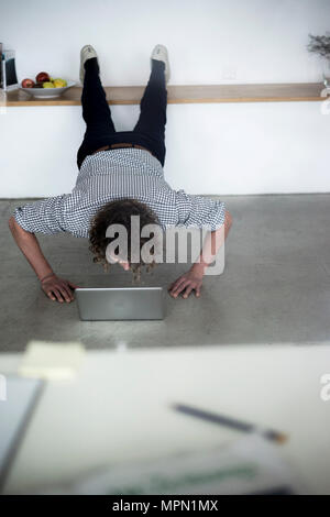 Unternehmer arbeiten von zu Hause mit seinem Laptop, während Sie eine Planke Stockfoto