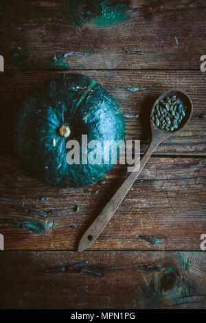 Grün Kürbis und Löffel, Kürbiskerne auf dunklem Holz Stockfoto