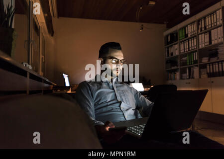 Unternehmer Arbeiten am Laptop im Büro bei Nacht Stockfoto