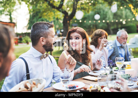 Gäste essen auf der Hochzeitsfeier draußen im Hinterhof. Stockfoto