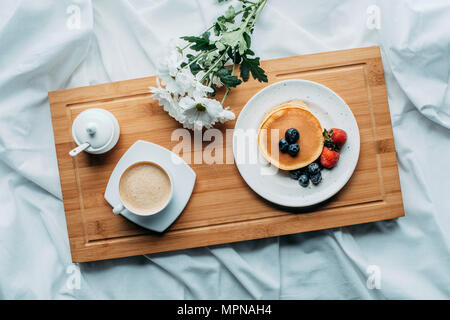 Draufsicht auf das Frühstück im Bett, mit leckeren Pfannkuchen und Kaffee auf Holz- fach Stockfoto