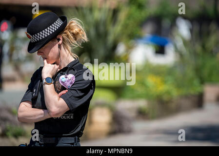 Ein Polizist mit einem Herzen zu ihrem Funkgerät verbunden steht außerhalb der Kathedrale von Manchester vor dem nationalen Service des Gedenkens in Erinnerung an die Opfer der Arena Bombenattentat in Manchester, Großbritannien, am 22. Mai 2018. Prinz William und der britische Premierminister Theresa May zusammen mit anderen Politikern, sowie Angehörige der Getöteten, und Rettungskräfte zur Szene des Terror Angriff, während Tausende von Menschen in Manchester Dienstag versammelten sich am ersten Jahrestag des Terrorangriffs in der Stadt die 22 Toten. Stockfoto