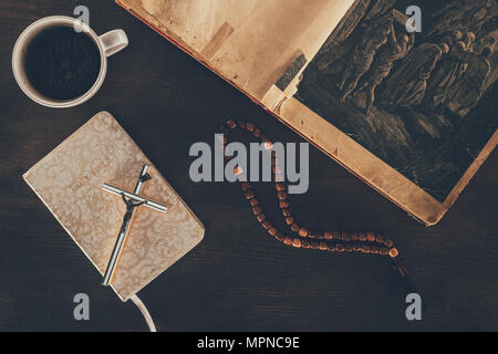 Blick von oben auf die offene Bibel und Rosenkranz auf dem Holztisch Stockfoto