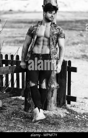 Gesunde junge Mann starke Verwindung Muskeln beim Tragen schwarze Jeans - Muskulös athletisch Bodybuilder Fitness Model posiert im Freien - ein Ort fo Stockfoto