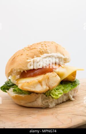 Eine Verrundung von Pollack Pollachius pollachius schmelzen, Mehl beschichtet ist und frittiert, auf einen Burger Brötchen mit Salat serviert, gegrillte Tomaten und Stockfoto