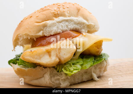 Eine Verrundung von Pollack Pollachius pollachius schmelzen, Mehl beschichtet ist und frittiert, auf einen Burger Brötchen mit Salat serviert, gegrillte Tomaten und Stockfoto