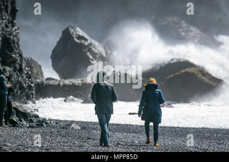 Vík í Mýrdal Strand; Reynisfjara Strand hat schwarze Kieselsteine, Basaltsäulen und die Reynisdrangar Offshore-Felsformationen. Ein abgelegenes Dorf am Meer mit rauer See, brechenden Wellen und starken Winden. Stockfoto